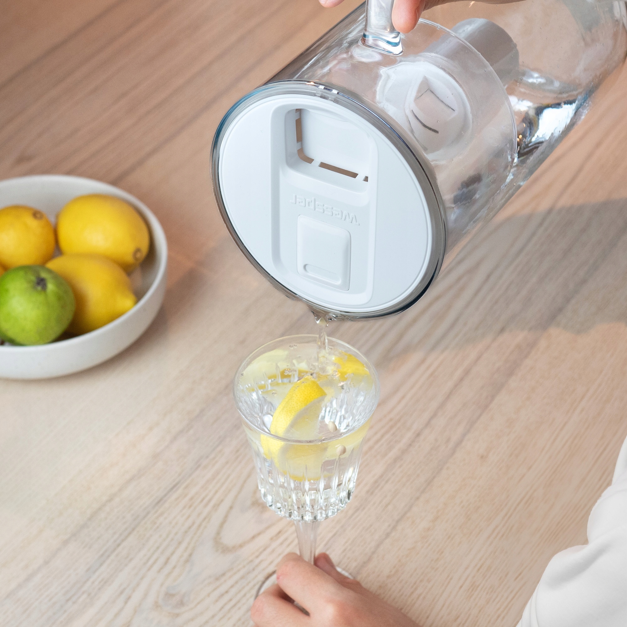 Kobieta nalewa szklankę przefiltrowaną wodą prosto z&nbsp;dzbanka Wessper D2 Borosilicate